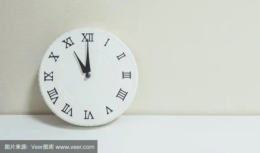 特写白色时钟装饰显示11点在白色木质桌子和奶油色壁纸纹理背景与复制